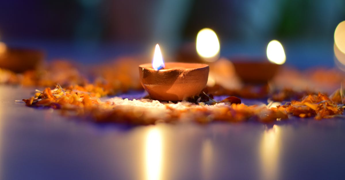 A warm and atmospheric close-up of a lit clay diya surrounded by flower petals, perfect for festive themes.