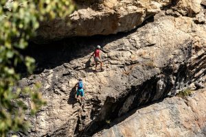 Two climbers scaling a rugged mountainside on a challenging via ferrata route. Adventure and skill showcased.