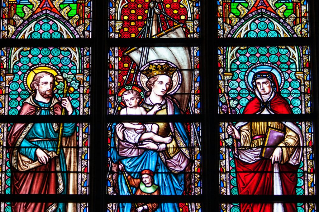 Colorful stained glass depicting saints and religious figures in a Brussels cathedral.