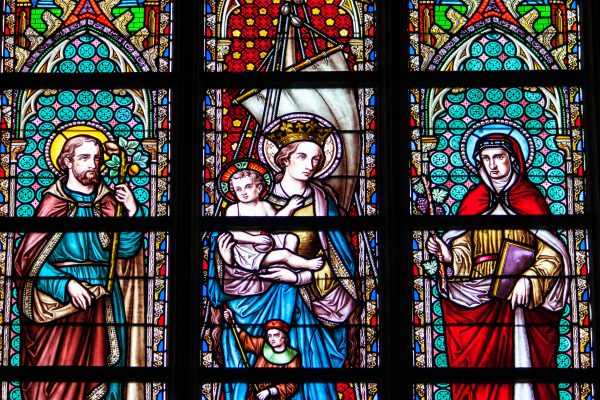 Colorful stained glass depicting saints and religious figures in a Brussels cathedral.