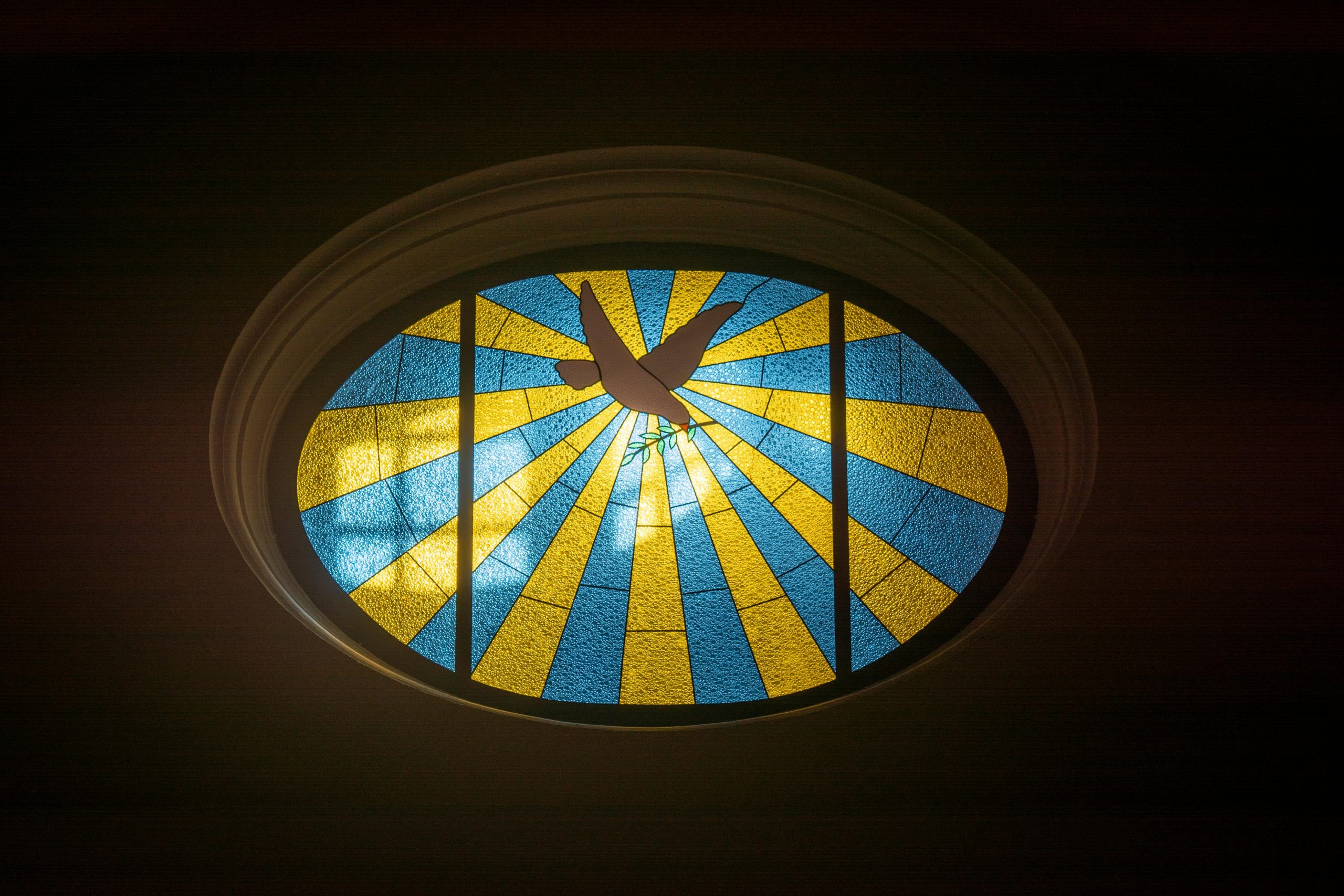 Colorful oval stained glass window featuring a dove in Teguise, Spain church.
