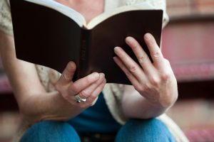 Hands holding an open Holy Bible, symbolizing faith and spirituality.