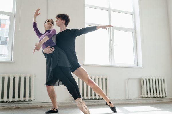 Two ballet dancers performing gracefully in a studio, practicing a duet routine.