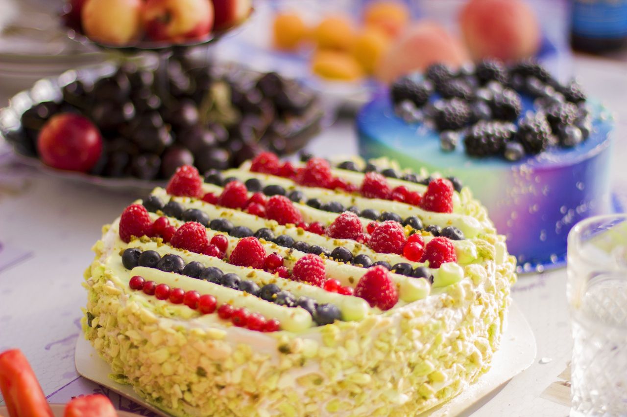 Vibrant fruit-topped and marbled cakes on table, perfect for food photography needs.
