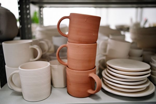 Close-up of stacked handmade ceramic mugs and plates showcasing pottery craft in a studio setting.